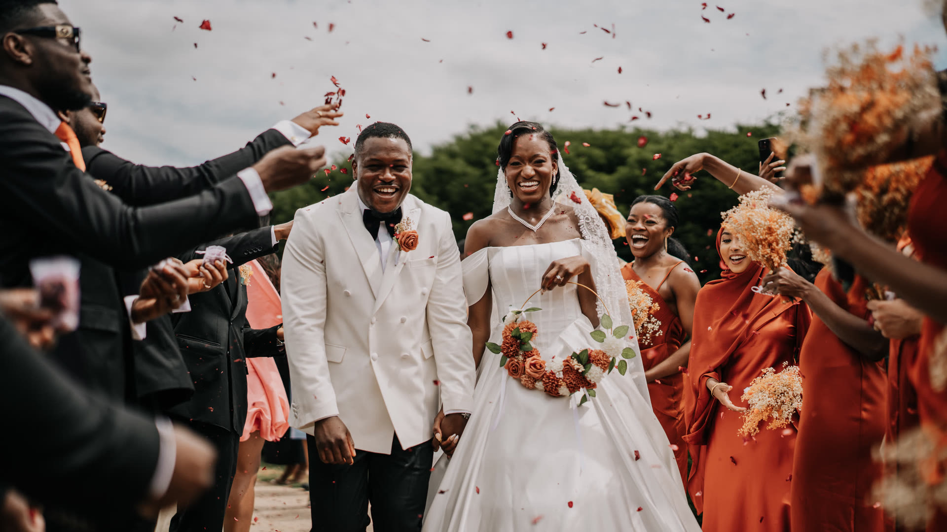 A couple walking out through a confetti throw, guests either side